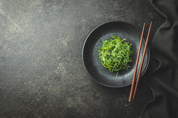 Green wakame. Seaweed salad in bowl on black table.