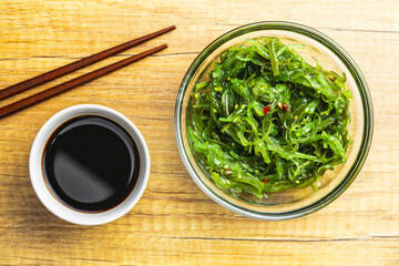 Green wakame. Seaweed salad and soy sauce in bowl.