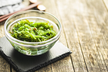 Green wakame. Seaweed salad in bowl on wooden table.