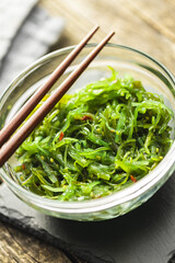 Green wakame. Seaweed salad in bowl on wooden table.