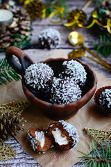Vertical composition. Chocolate truffles with coconut flakes in a ceramic bowl on a wooden background. Closeup