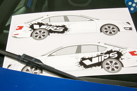 Installation of black vinyl gloss stickers on the side of a blue sports car parked in a garage.