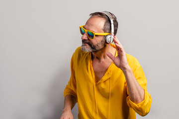 Stylish senior man enjoying music on earphones with sunglasses
