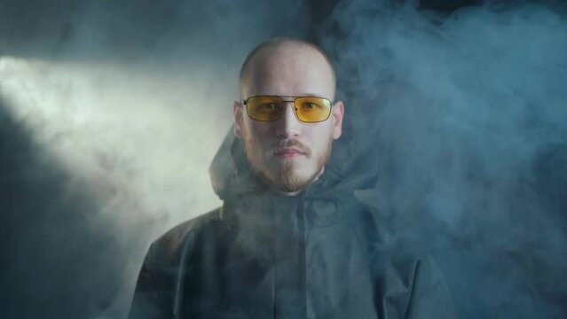 A man in a black medical chemical protection suit and yellow glasses and transparent medical gloves