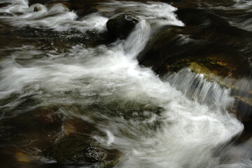 Fluss, der über Steine dahin fließt und dabei eine sehr starke Strömung aufweist