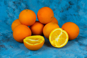 Orange stack on textured blue background, side or profile view of lots of fresh and bright oranges. Fruitarianism concept with no people.