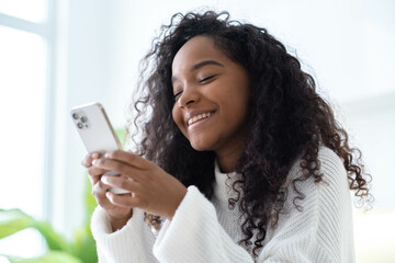 African American Girl using smartphone pressing finger, reading social media internet, typing text...