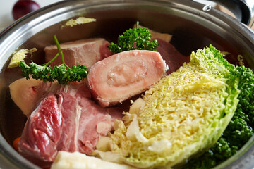 Fresh marrow bone in a pot of water with beef meat and vegetables - ingredients for broth or soup