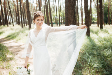 a cute bride is spinning in a wedding dress being outdoors in the forest.