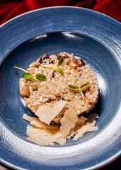 Risotto with porcini mushroom and parmesan cheese on blue plate
