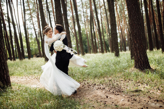 the groom hugs the bride. wedding day of a young couple. lovers walk in the forest