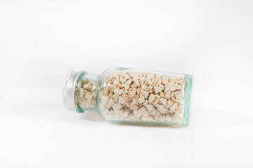 glass jar with metal cape and light color rocks filled inside with slightly green color on white background