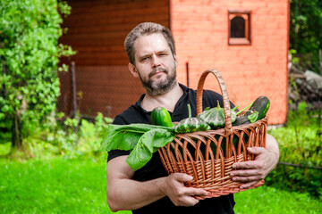 Portrait of a bearded male farmer with a basket full of ripe, fresh vegetables