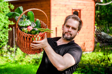 Portrait of a bearded male farmer with a basket full of ripe, fresh vegetables