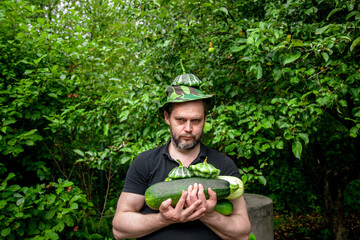 Portrait of a man harvesting organic vegetables.The gardener holds ripe, juicy zucchini in his hands