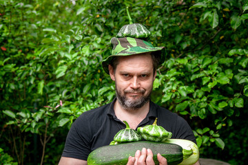 Portrait of a man harvesting organic vegetables.The gardener holds ripe, juicy zucchini in his hands	
