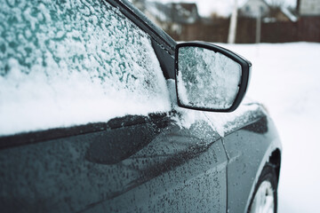 Element of the car covered with snow on the territory of its own site. Side mirror and car glass...