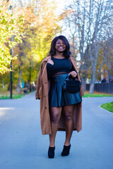 Front view of a  beautiful African lady wearing a black dress in a park.