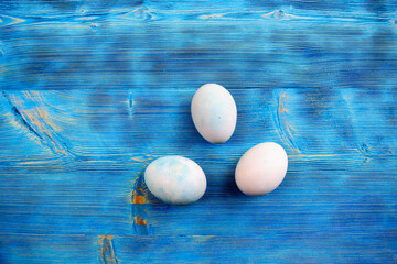 Easter eggs in soft colors on a blue shabby wooden table