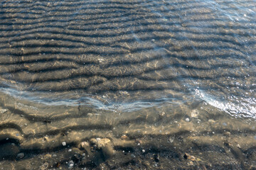 scallops of sand under transparent sea water on the beach