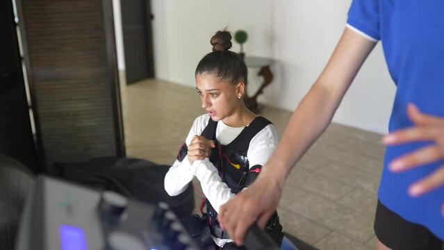 EMS training. Girl doing exercises in a suit with cables.