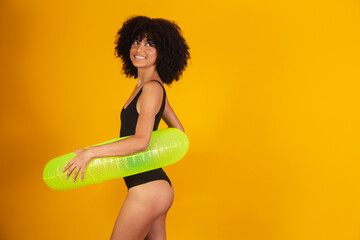 Afro woman with black power hair using a floating buoy on yellow background. vacation concept