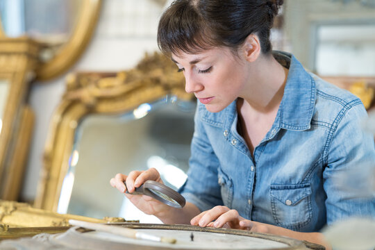 woman looking at a picture frame with magnifying glass