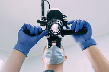 Male Dentist Adjusts Microscope Before Starting Work. Close-up, Bottom View.