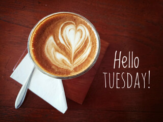 Tuesday coffee with text greeting on brown wooden table - Hello Tuesday. With cup of coffee latte and spoon. Happy Tuesday. © Maria Marganingsih