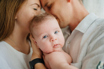 a happy family with a newborn baby by the window. mom, dad and baby.