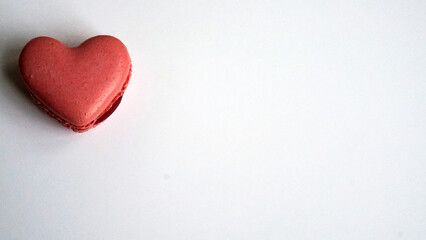 Pink heart-shaped macaron on a white background with copy space for Valentine's Day message.