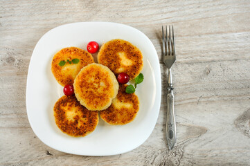 Cottage cheese cheesecakes on a plate with cranberries and mint. Top view, selective focus with copy space