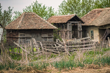 Fototapeta na wymiar View of an old, abandoned and wooden house and barn with a broken fence