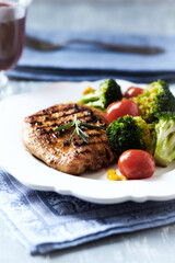 Grilled Turkey Breast with oven baked broccoli, cherry tomatoes and sweet corn. Bright wooden background. Close up.	