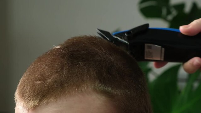 A man is getting a haircut with an electric clipper at home. Home haircut. Savings on hairdresser.