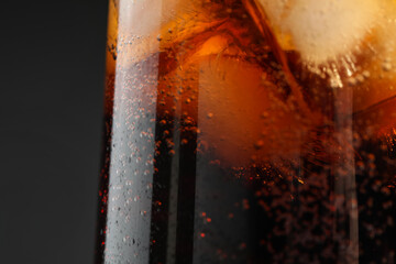 Glass of refreshing soda drink with ice cubes on black background, closeup