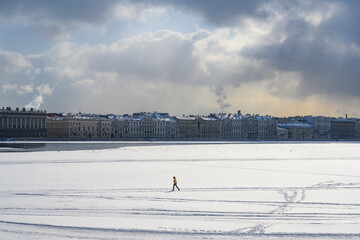 A man walking fast on ice on the Neva River in St. Petersburg under thunder clouds