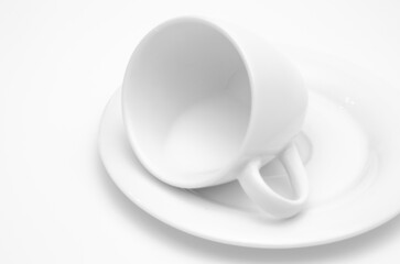 a white coffee mug lies on its side, there is some milk inside, on a white background