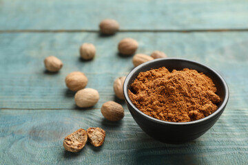 Bowl of nutmeg powder and seeds on light blue wooden table