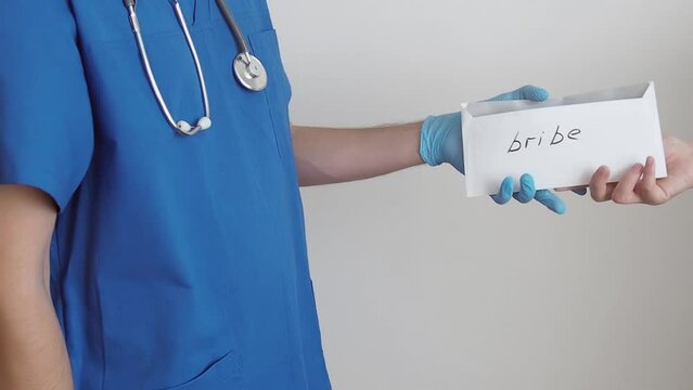Hand of a patient giving envelope with money bribe to a doctor. Concept of expensive medicine and healthcare and corruption 