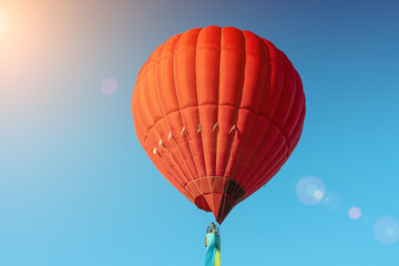 Red hot air balloon with the flag of Ukraine on a blue sky background