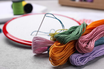 Different threads and embroidery hoop on light grey table