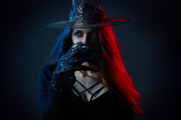 Dangerous evil witch with claws and magic hat in a dark atmosphere