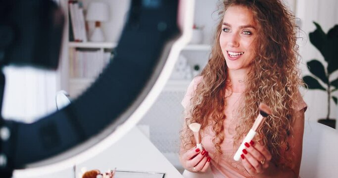 young woman streaming a beauty vlog from home, online content creator applying a makeup on, video tutorial