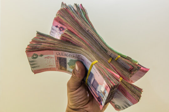 Hand holding stacks of Sudanese Pound banknotes