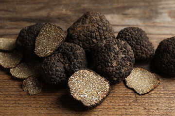 Whole and cut truffles on wooden table, closeup