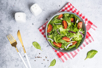 Summer green salad in white bowl plate on grey table