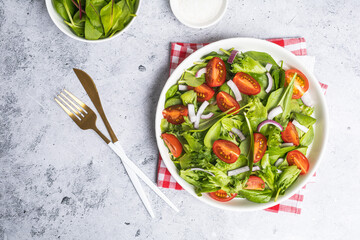 Summer green salad in white bowl plate on grey table
