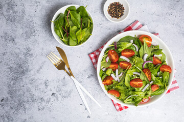 Summer green salad in white bowl plate on grey table