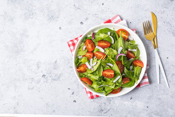 Summer green salad in white bowl plate on grey table